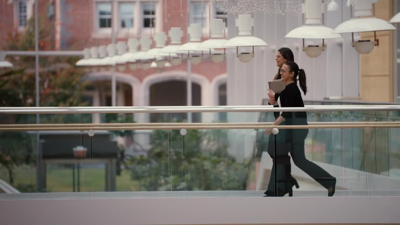 Two women walking inside the New England Biolabs building